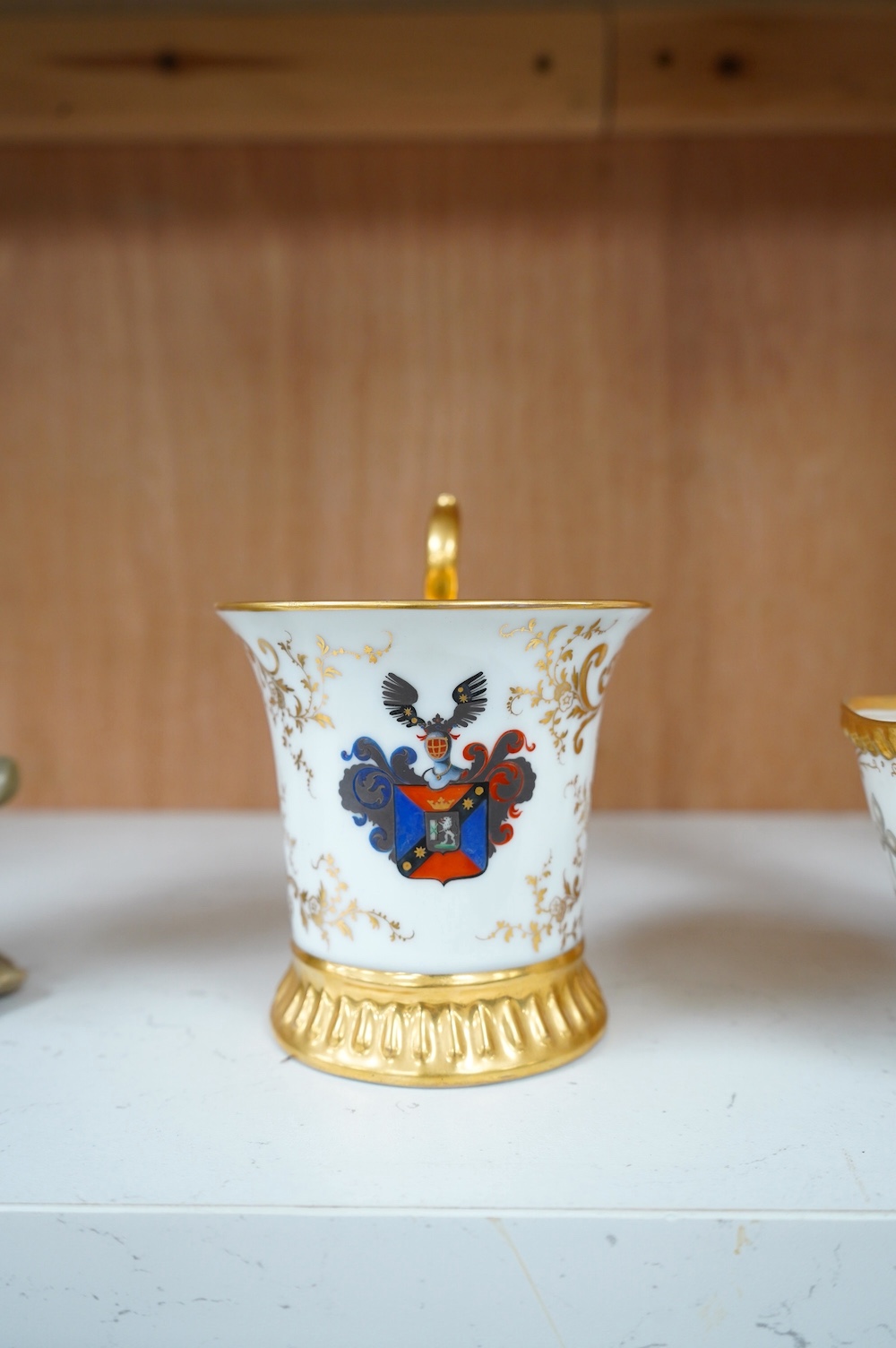 An armorial mug with lithophane figural scene to the base, together with a similar cup, largest 12cm high. Condition - mug poor, cup is good